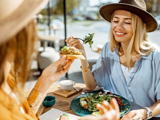 Two friends smiling while eating lunch outside