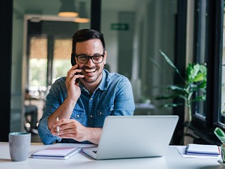 Man smiling while talking on cell phone in office