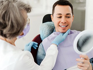 Man smiling at reflection in mirror with dentist